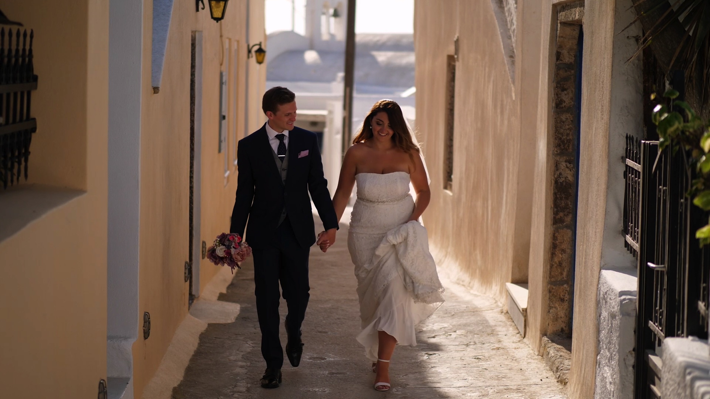Gareth and Sara walk hand in hand through the streets of Santorini, all smiles, having said "I do" just moments before.